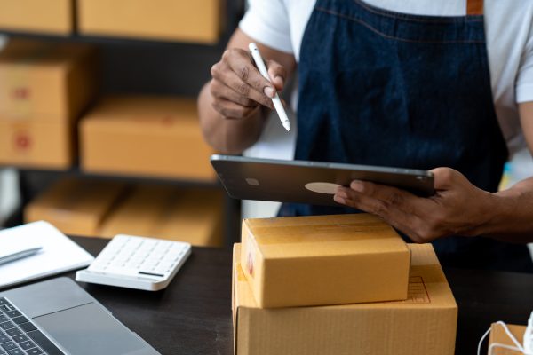 Freelance businessman checking and verifying shipping information Package boxes to prepare for deliv